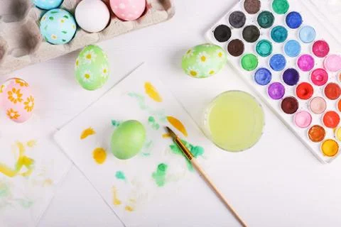 Hand painted Easter eggs, paints and brushes on a white table. Preparation fo Stock Photos