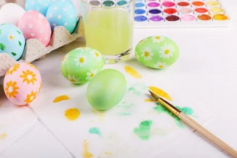 Hand painted Easter eggs, paints and brushes on a white table. Preparation fo Stock Photos
