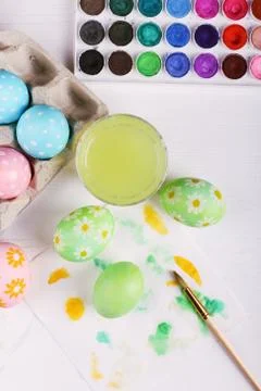 Hand painted Easter eggs, paints and brushes on a white table. Preparation fo Stock Photos