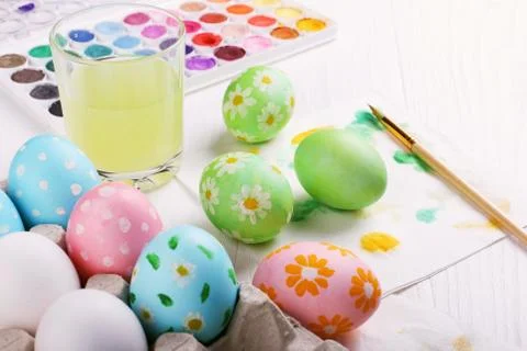 Hand painted Easter eggs, paints and brushes on a white table. Preparation fo Stock Photos