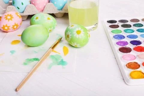 Hand painted Easter eggs, paints and brushes on a white table. Preparation fo Stock Photos