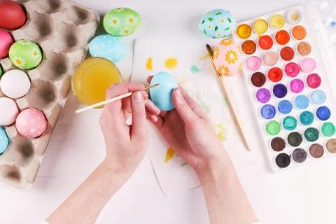 Hand painted Easter eggs, paints and brushes on a white table. Preparation fo Stock Photos