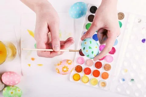 Hand painted Easter eggs, paints and brushes on a white table. Preparation fo Stock Photos
