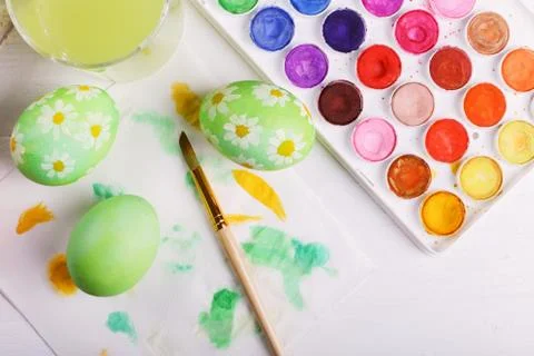 Hand painted Easter eggs, paints and brushes on a white table. Preparation fo Stock Photos