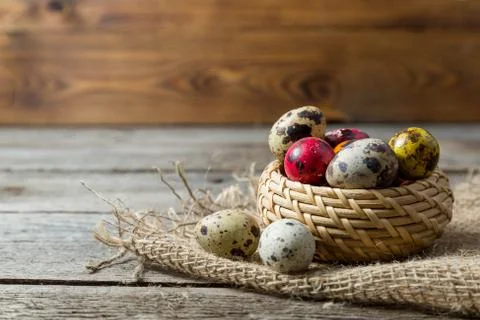Hand painted easter eggs in wicker basket on burlap napkin on wooden backgrou Stock Photos