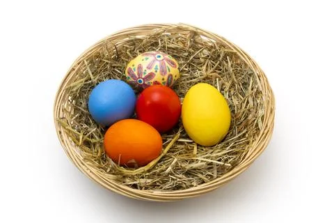 Hand Painted Easter Eggs in Wicker Basket with Hay Isolated on White Stock Photos