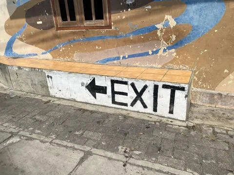 Hand-painted EXIT sign with a left arrow on a concrete bench. 스톡 사진