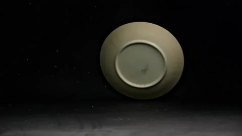 A hand-painted plate falls and shatters on the floor, captured in slow moti.. Stock-Footage 298181978