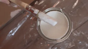 Hand of painter dipping a brush into a bucket with white paint , slow motion Stock Footage 86017554