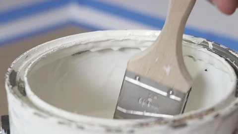 Hand of painter dipping a brush into a bucket with white paint. Renovation. Stock Footage 129139356