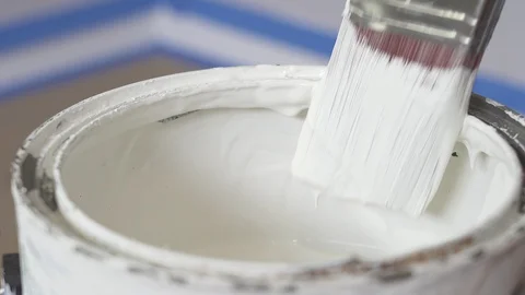 Hand of painter dipping a brush into a bucket with white paint. Renovation Stock Footage 129139401