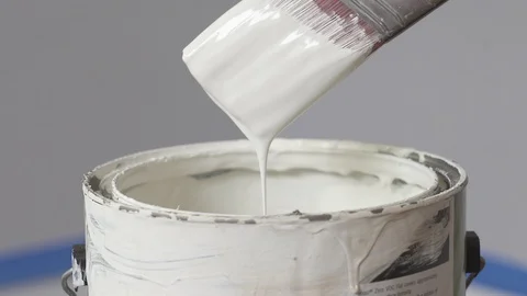 Hand of painter dipping a brush into a bucket with white paint. Renovation Stock Footage 129139429