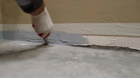 Hand painting baseboard with gray paint using brush Stock Footage 338384714