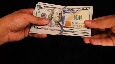 Hand Passing a Bundle of $100 Bills – Money Exchange or Financial Transaction Stock Footage 297771627