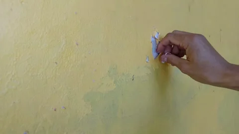 Hand peeling a paint from a yellow wall Vidéo 332470332