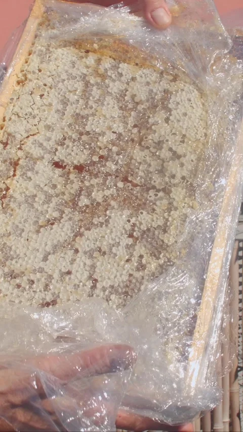 Hand peeling plastic wrap from round baked cake on bamboo tray outdoors during Stock Footage 344882456