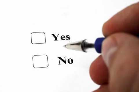 Hand with a pen over the document, select Yes or No. Close-up. Soft focus. Stock Photos