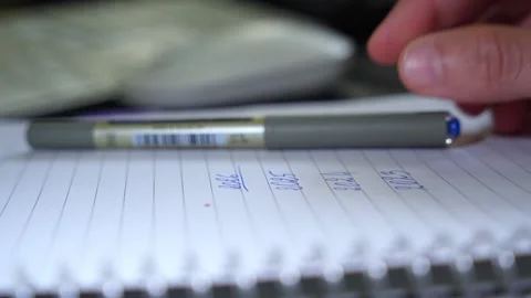 Hand with Pen Over Notes: Close-Up Writing Scene with Soft Focus Stock Footage 313724576
