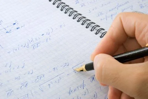 	The hand with the pen writes formulas in a writing-book. Stock Photos