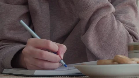 Hand with pen writing text in notebook. Portrait of girl writing in comfortable Stock Footage 130390125