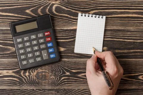 Hand with a pen writting blank notebook on wooden background Stock Photos