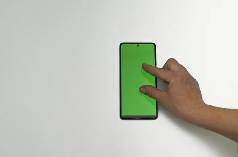 Hand performs a gesture on the green smartphone screen, holding it vertically 스톡 사진
