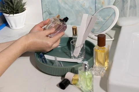 In-hand perfume testing on a marble vanity with round mirror and cosmetics Stock Photos
