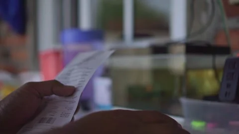 Hand of person checking printed receipt, reviewing bill and QR code, 動画素材 342637214