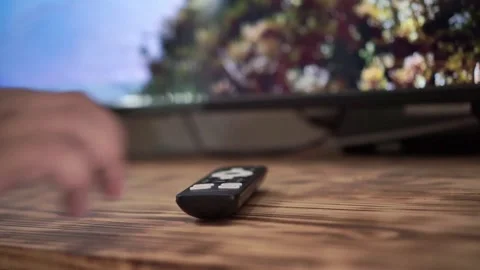 Hand of person placing television remote on to wooden desk surface, Stock Footage 342637477