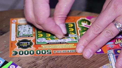 Hand of a person scratching scratch card tickets from Française des Jeux Stock Footage 296810302