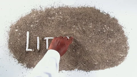 A hand of a person in a shirt writing on black sand words Litigation Stock Footage 248673053