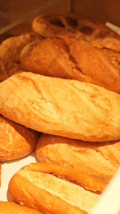 Hand pick Freshly baked bread loaves stacked in a bakery display case 스톡 동영상 305014874