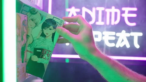 Hand pick a manga comic from shelf with futuristic neon sign in background 4K Stock Footage 320240397
