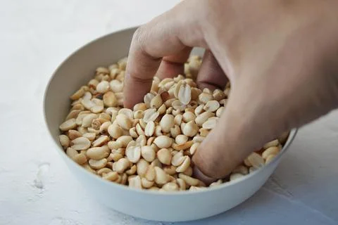 Hand pick Processed peanuts in a bowl on table Stock Photos