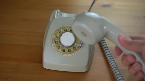 A hand picking up and hanging a retro white/green rotary phone Stock Footage 128372704