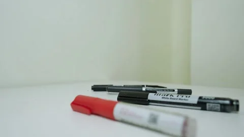 Hand picking up a black marker from a white surface with other markers Stock Footage 318057234