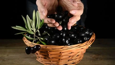A hand picking up a black olives from a wicker basket Stock Footage 140215713