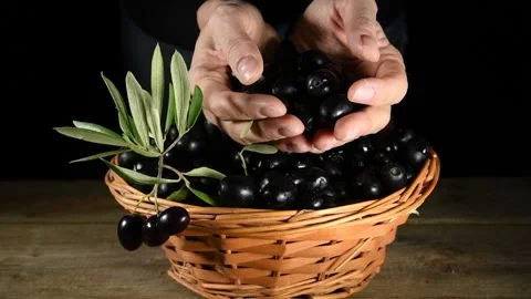 A hand picking up a black olives from a wicker basket Stock Footage 140215795