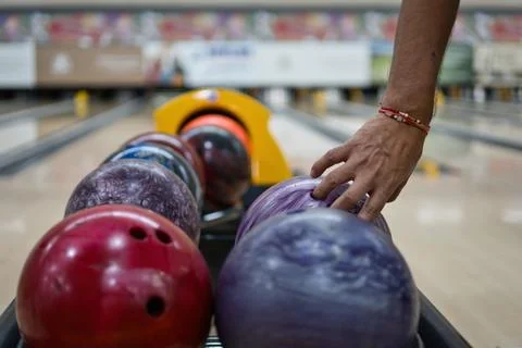 Hand picking up bowling ball in return machine at bowling alley. Stock Photos