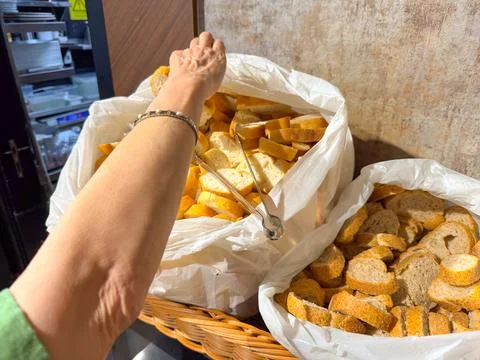Hand picking bread slice from basket at breakfast buffet. Food, lifestyle, an Stock Photos