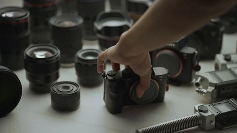 A hand picking  up camera between another camera and lens. tools of trade close  Video stock 128406165