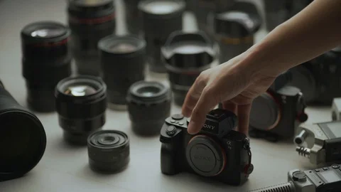 A hand picking up camera between another camera and lens. Video stock 128406239