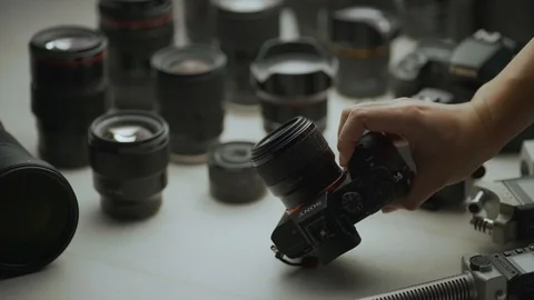 A hand picking up the camera between another camera and lens. tools of trade  Video stock 128406309
