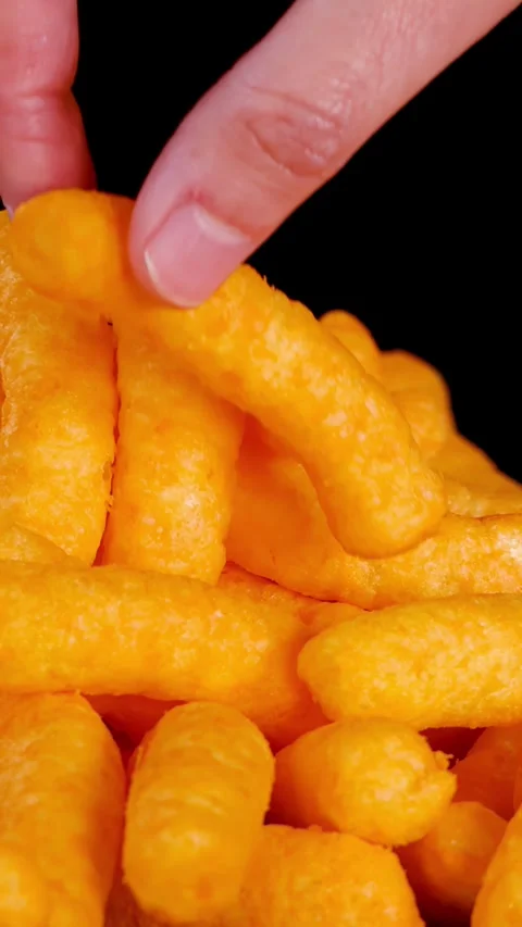 Hand Picking Up Cheese Puff Snack from Pile Stock Footage 321528896