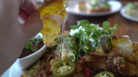 Hand picking cheesy nacho chips with salsa and minced meat dipping Mexican .. Stock Footage 302519824