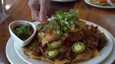 Hand picking cheesy nacho chips with salsa and minced meat dipping Mexican .. Stock Footage 302519894