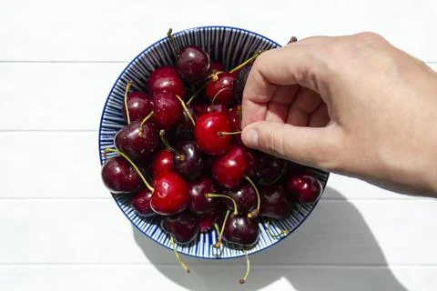 Hand picking a cherry from bowl of cherries Stock Photos