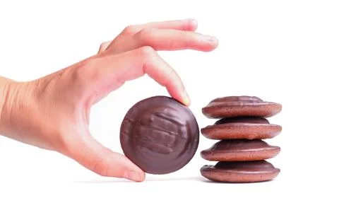 Hand Picking Chocolate Cookie Next to Stack on White Background Foto stock