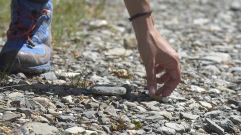 Hand picking up cigarette butt from mountain trail, Italy Видео 335680563