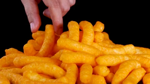 Hand Picking Up Crispy Cheese Puffs from Snack Pile Stock Footage 319512605